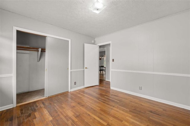 unfurnished bedroom with a closet, a textured ceiling, and hardwood / wood-style floors