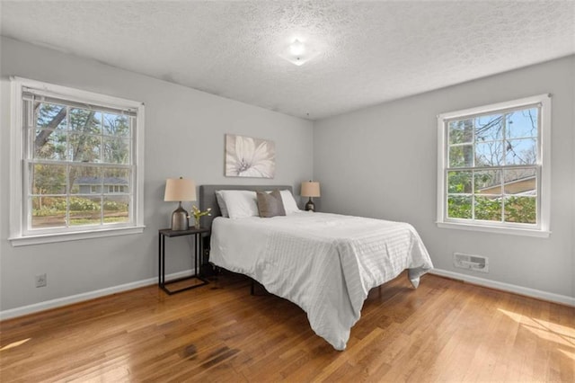 bedroom featuring baseboards, a textured ceiling, and hardwood / wood-style flooring