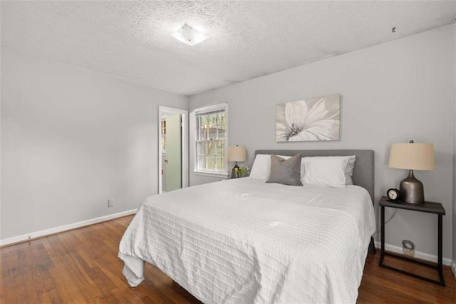 bedroom with baseboards, a textured ceiling, and wood finished floors