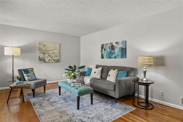 living area featuring a textured ceiling, baseboards, and wood finished floors