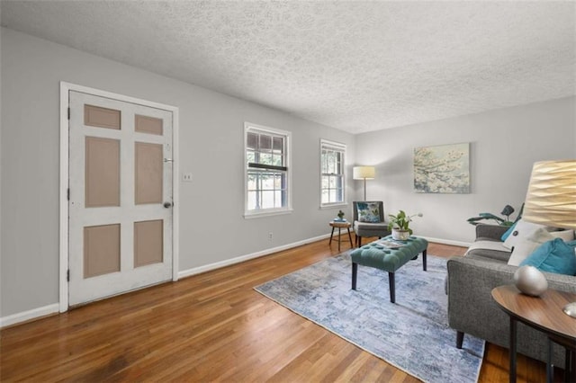 living room featuring baseboards, a textured ceiling, and wood finished floors