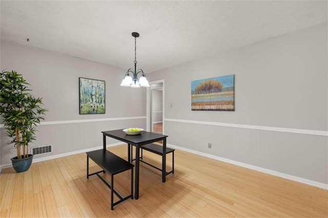 dining space featuring an inviting chandelier, light wood-style flooring, visible vents, and baseboards