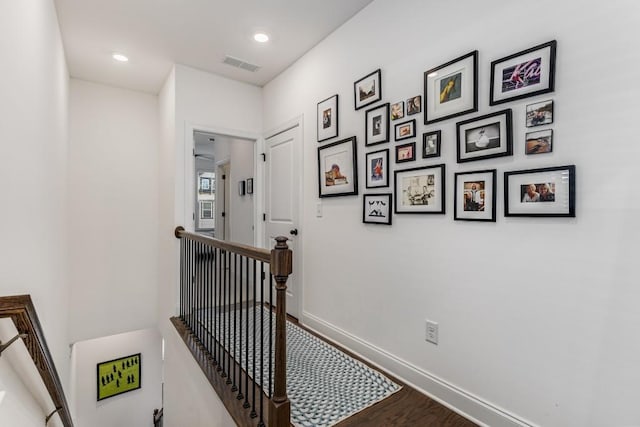 corridor with recessed lighting, visible vents, an upstairs landing, wood finished floors, and baseboards