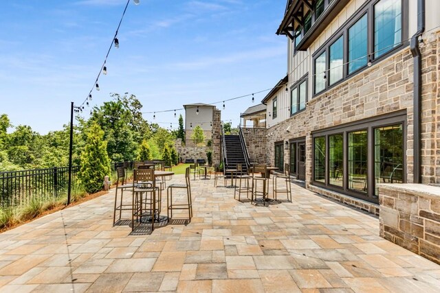 view of patio with outdoor dining area, fence, and stairs