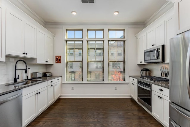 kitchen with stainless steel appliances, a sink, baseboards, white cabinets, and dark wood-style floors