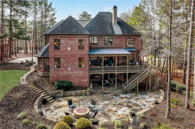 back of house with a wooden deck, a patio area, and an outdoor fire pit