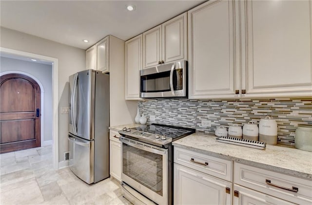 kitchen with light stone countertops, appliances with stainless steel finishes, backsplash, and recessed lighting