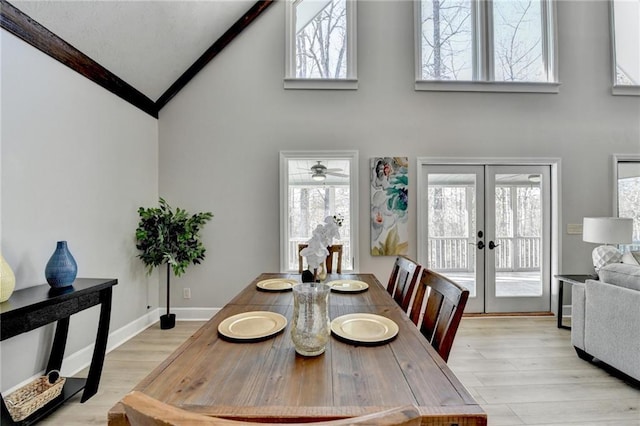 dining space with high vaulted ceiling, light wood-type flooring, french doors, and plenty of natural light