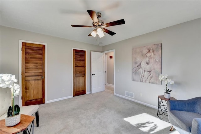 sitting room with carpet floors, visible vents, baseboards, and a ceiling fan