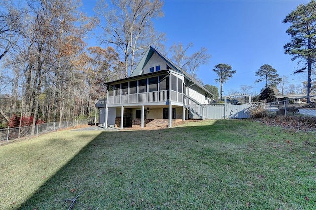 back of house featuring ceiling fan, a yard, a fenced backyard, and a sunroom