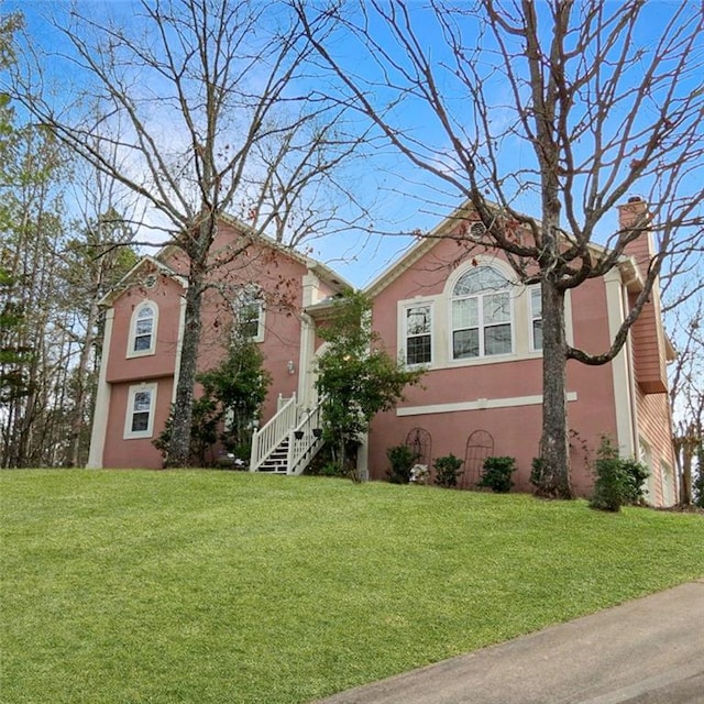 view of front facade featuring a chimney, a front yard, and stucco siding