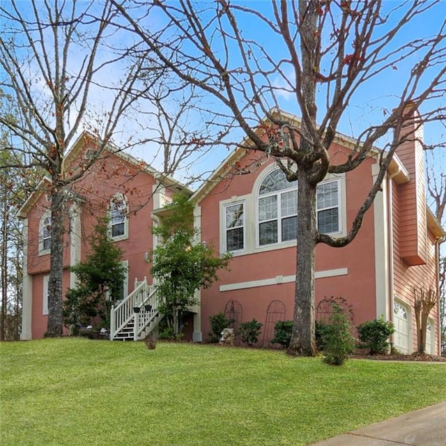 view of front facade featuring stucco siding, an attached garage, a chimney, and a front yard