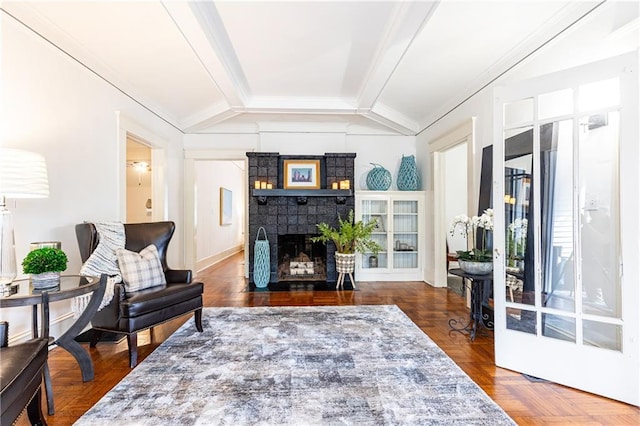 living room featuring dark parquet floors, lofted ceiling, ornamental molding, and a brick fireplace