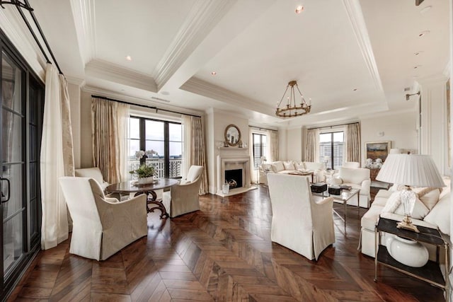 living room featuring dark parquet flooring, an inviting chandelier, ornamental molding, and a tray ceiling