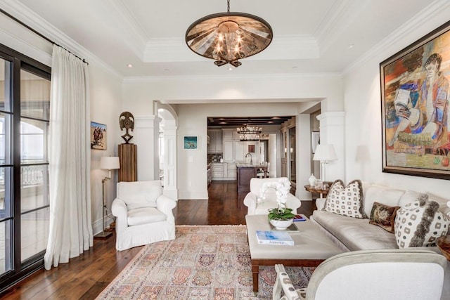 living room featuring a raised ceiling, crown molding, and a chandelier