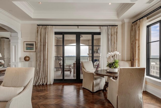 sitting room featuring dark parquet flooring, french doors, ornamental molding, and a tray ceiling