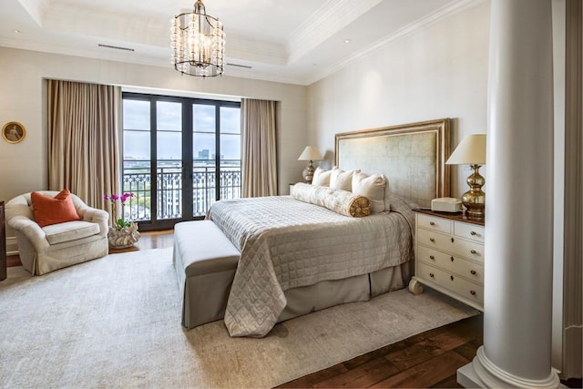 bedroom featuring decorative columns, access to outside, a raised ceiling, hardwood / wood-style floors, and a chandelier