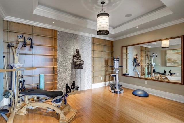 workout area featuring a raised ceiling, ornamental molding, and built in features