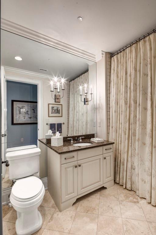 bathroom with toilet, ornamental molding, and vanity