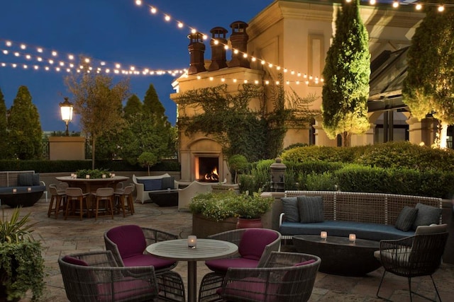 patio at twilight with an outdoor bar and an outdoor living space with a fireplace