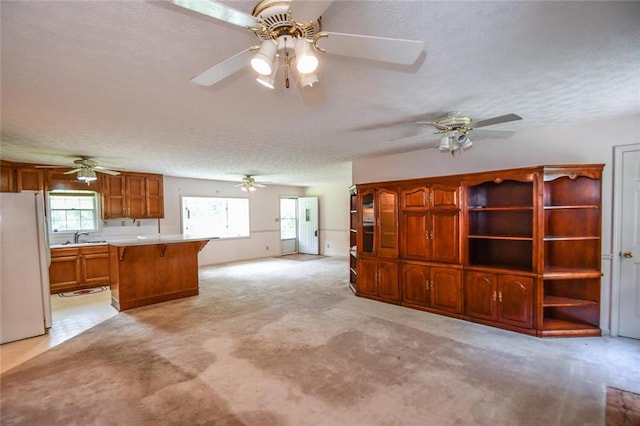 3223 Heritage Way, Buford, GA 30519 - kitchen featuring freestanding refrigerator, a ceiling fan, brown cabinetry, light countertops, and a textured ceiling