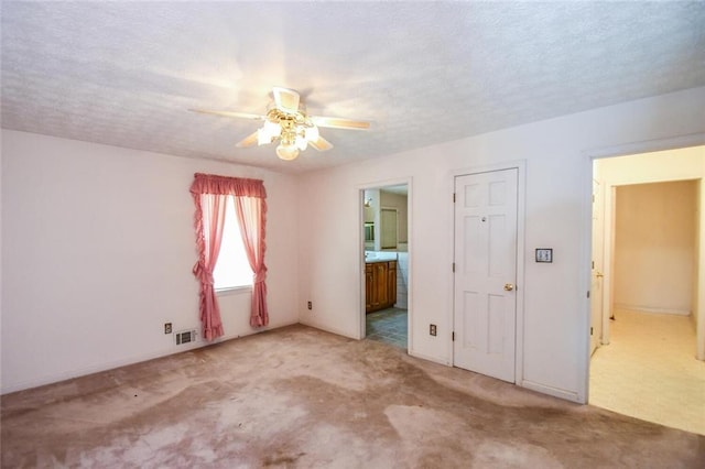 3223 Heritage Way, Buford, GA 30519 - unfurnished bedroom featuring light carpet, connected bathroom, a textured ceiling, and a ceiling fan