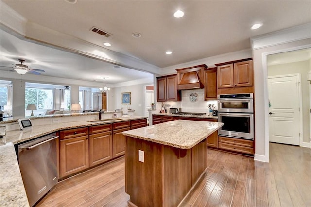 kitchen with custom exhaust hood, visible vents, appliances with stainless steel finishes, a sink, and light wood-type flooring