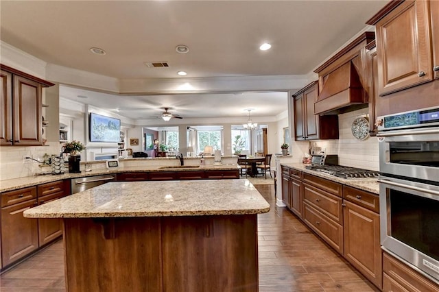 kitchen with stainless steel appliances, a sink, wood finished floors, visible vents, and backsplash