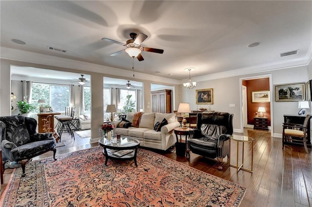 living area with dark wood-style flooring, a notable chandelier, visible vents, ornamental molding, and baseboards