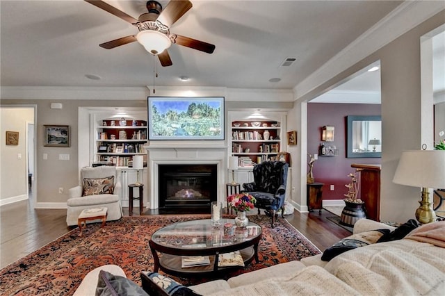 living area featuring built in features, baseboards, ornamental molding, and wood finished floors