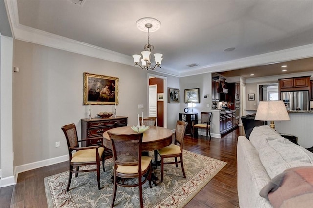 dining room featuring dark wood-type flooring, crown molding, a notable chandelier, and baseboards