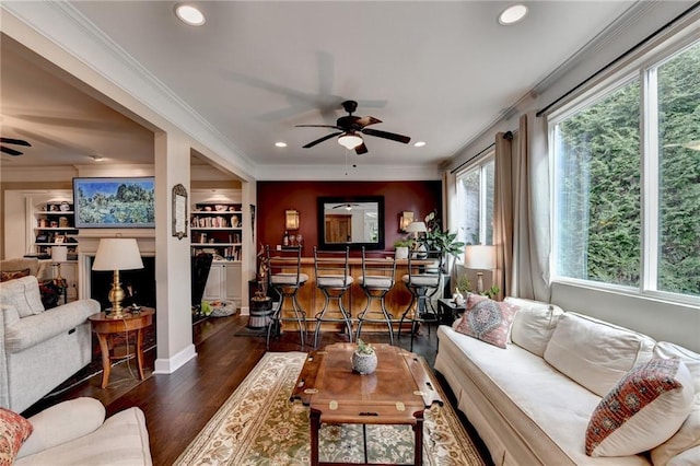 living area with built in features, recessed lighting, ornamental molding, a ceiling fan, and wood finished floors