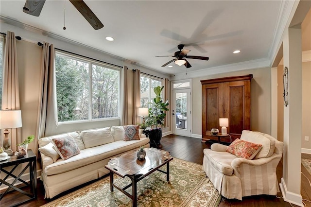 living room with baseboards, ornamental molding, ceiling fan, and dark wood-type flooring