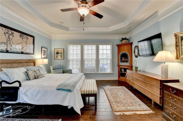 bedroom with ornamental molding, a raised ceiling, and dark wood finished floors