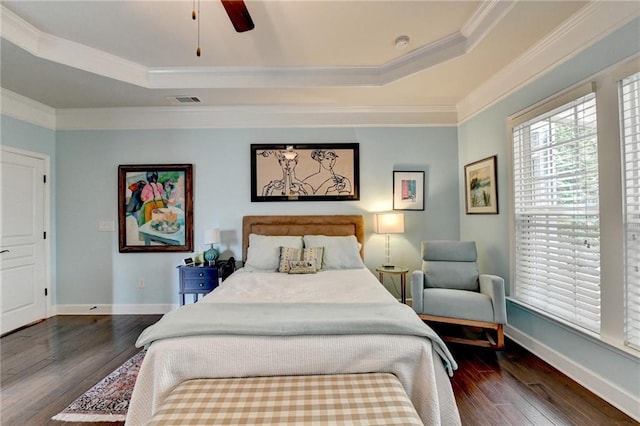 bedroom with dark wood-style floors, a raised ceiling, crown molding, and baseboards