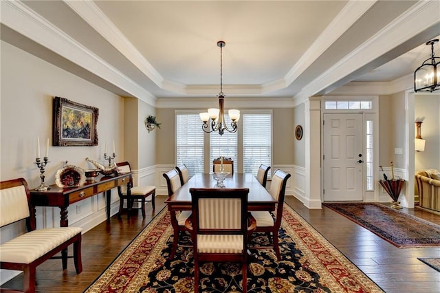 dining area with dark wood-type flooring, wainscoting, and an inviting chandelier