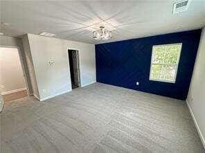 unfurnished bedroom featuring carpet and an inviting chandelier