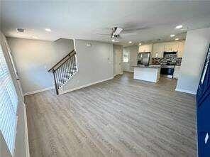 unfurnished living room with hardwood / wood-style floors and ceiling fan