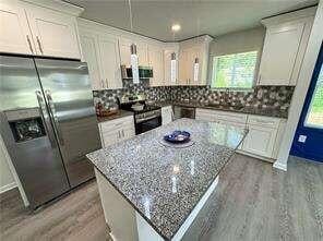 kitchen with a center island, stainless steel appliances, white cabinetry, and stone countertops