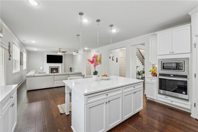 5545 Adirondack Dr, Cumming, GA 30040 - kitchen with appliances with stainless steel finishes, a ceiling fan, recessed lighting, light countertops, and a warm lit fireplace