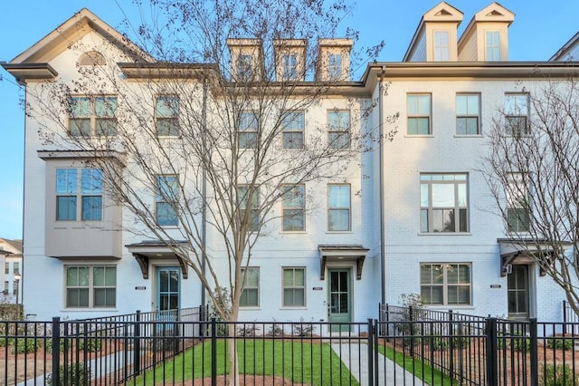 multi unit property featuring brick siding and a fenced front yard