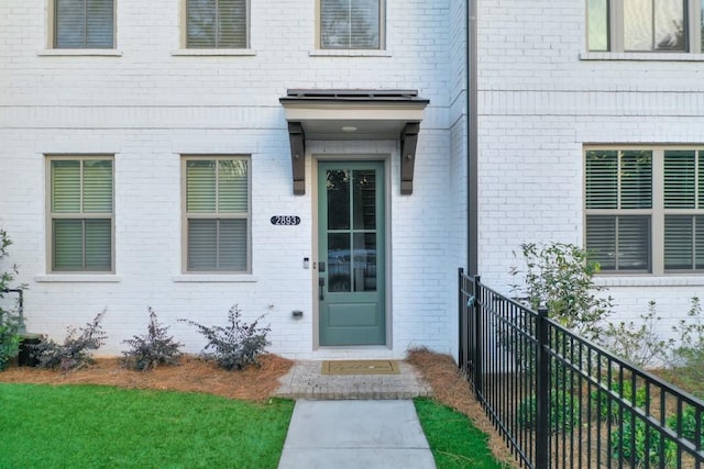 entrance to property with brick siding and fence