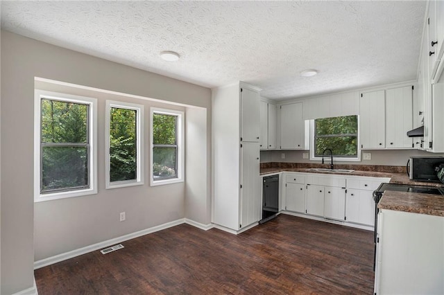 kitchen featuring dark wood-style floors, dark countertops, a sink, under cabinet range hood, and black appliances