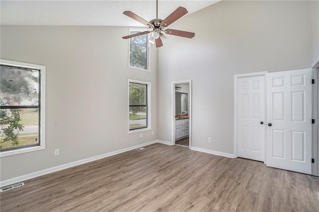 unfurnished bedroom with visible vents, connected bathroom, baseboards, and wood finished floors