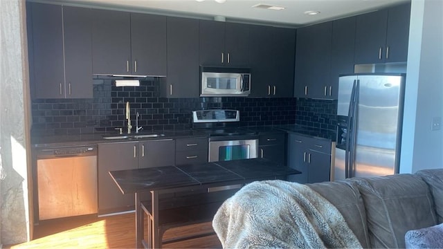 361 17th St NW Unit 1717, Atlanta, GA 30363 - kitchen featuring appliances with stainless steel finishes, wood finished floors, tasteful backsplash, open floor plan, and dark countertops
