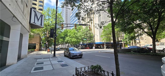 view of asphalt street featuring curbs, sidewalks, and street lights