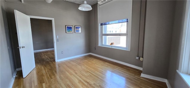 spare room featuring light wood-style flooring and baseboards