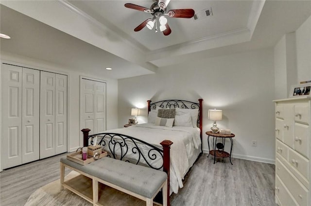 5475 Trowbridge Dr, Dunwoody, GA 30338 - bedroom with crown molding, visible vents, a raised ceiling, wood finished floors, and multiple closets