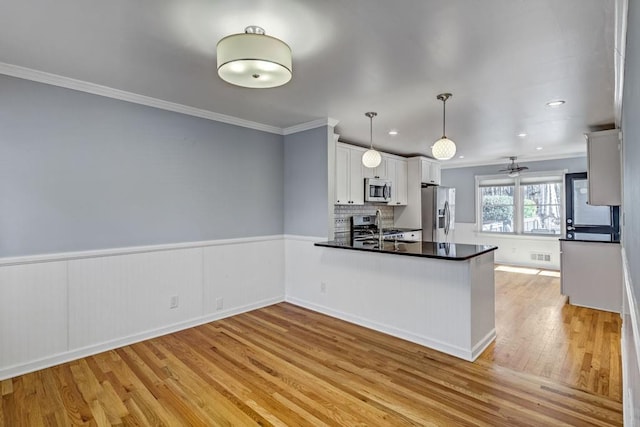 kitchen with crown molding, a sink, light wood-style flooring, and appliances with stainless steel finishes