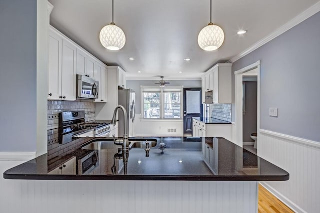 kitchen with white cabinets, stainless steel appliances, and dark stone counters
